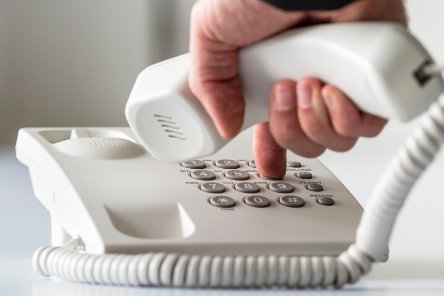 Wide panorama view of a male hand dialing a telephone number